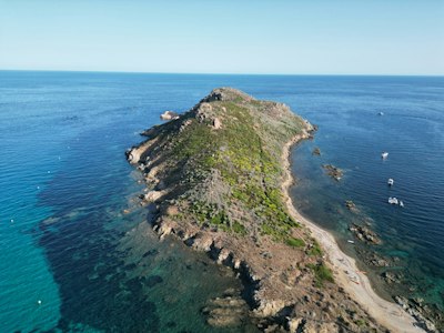 A long, narrow island with green vegetation and rocky terrain.